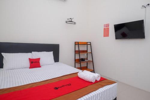 马格朗RedDoorz near Alun Alun Magelang 2的一间卧室配有一张带红色毯子的床和一台平面电视。