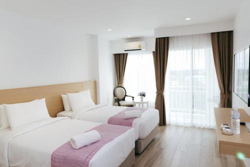 清迈Arsh Boutique Hotel的酒店客房设有两张床和窗户。