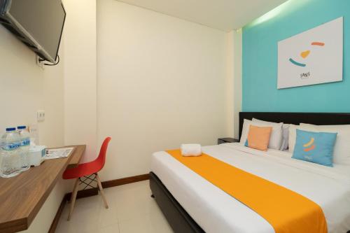茂物Sans Hotel Suryakencana Bogor的一间卧室配有一张床、一张书桌和一台电视