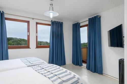 绍斯布鲁姆San Lameer Villa 2818 - 2 Bedroom Classic- 4 pax - San Lameer Rental Agency的一间卧室配有蓝色窗帘和一张带电视的床