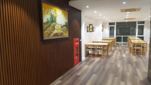 宁平The Queen Hotel Ninh Binh的餐厅设有桌椅,墙上挂有绘画作品