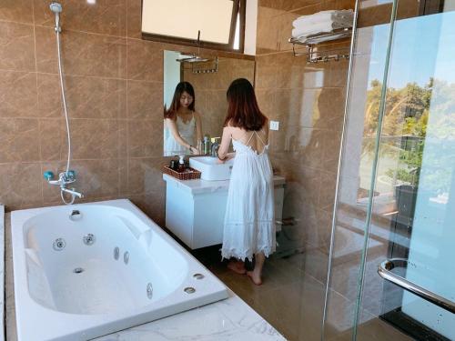 岑山Villa FLC Sầm Sơn Vị Trí Trung Tâm View Biển的站在浴室水槽前的妇女