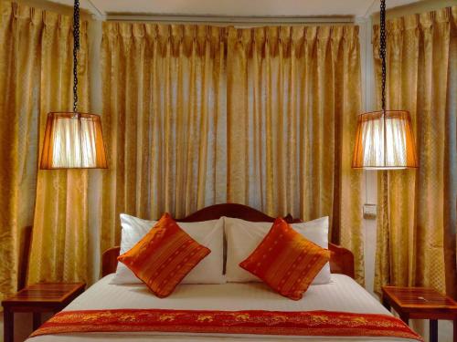 桔井Le Tonle的一间卧室配有两盏灯和一张带枕头的床。