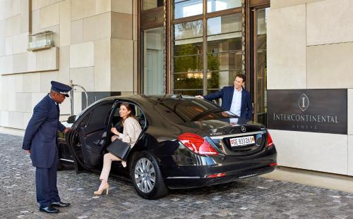 日内瓦InterContinental Genève, an IHG Hotel的男人和女人在建筑物外开车
