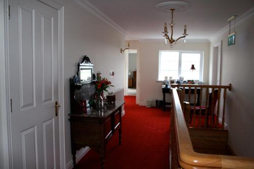 安特里姆Ballyharvey B&B的一间铺有红地毯的走廊和一间带时钟的房间