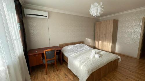 阿斯塔纳На Тархана的一间卧室配有一张床、一张桌子和一把椅子