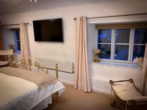 TintinhullThe Crown & Victoria Inn的一间卧室配有一张床,墙上配有电视