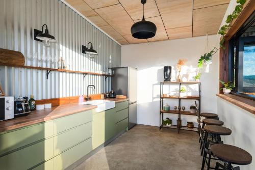 凯阿玛Cicada Luxury Camping的厨房配有绿色橱柜、水槽和凳子