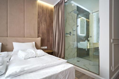 布克维Olimp Hotel的一间卧室设有一张床和一个玻璃淋浴间