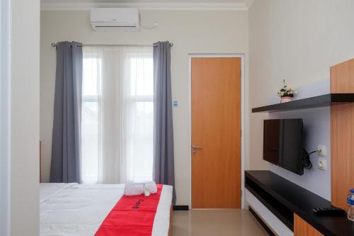 马格朗RedDoorz Syariah near Universitas Tidar Magelang的一间卧室设有一张床、一台电视和一个窗口。