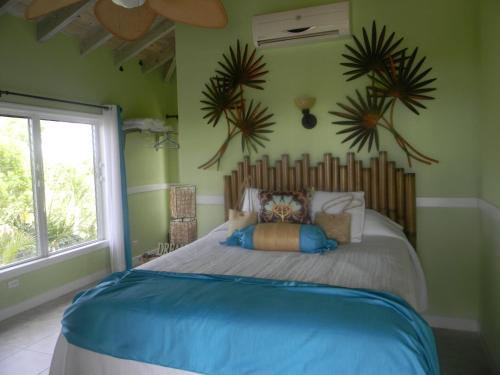 Clarence Town清风港口别墅的一间设有一张大床的卧室,位于带绿色墙壁的房间