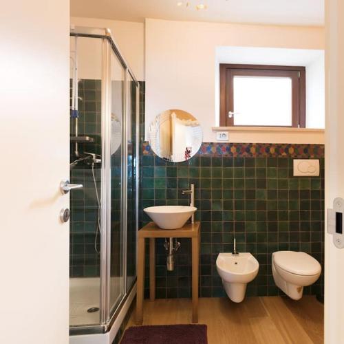 雷卡纳蒂Appartamentino IL NIDO vista mare的绿色瓷砖浴室设有水槽和卫生间