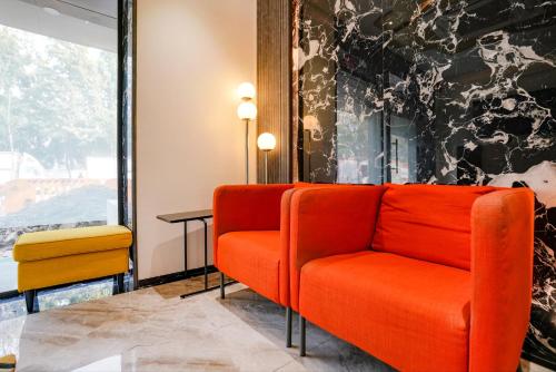 孟买FabExpress The Dream Residency的一间备有橙色椅子和桌子的等候室