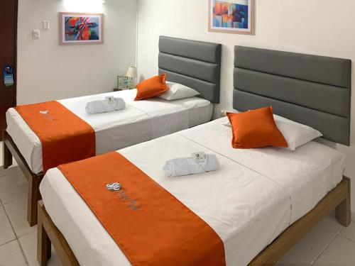皮乌拉Hostal Resident的橙色和白色的客房内的两张床