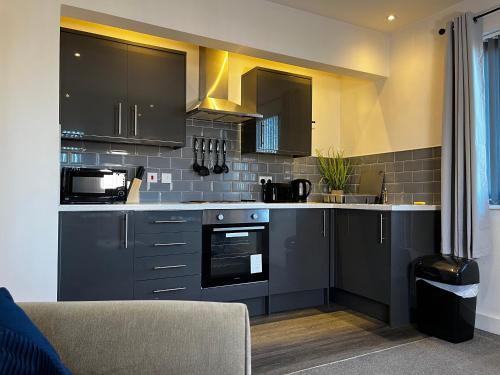 唐克斯特Lovely Serviced Apartment - Near Doncaster Hospital的厨房配有黑色橱柜和台面