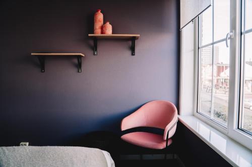 赞德沃特Boutique Lodge Zandvoort的粉红色的椅子坐在窗户的房间