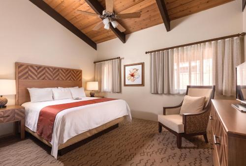 科纳科纳海岸度假酒店的一间卧室配有一张大床和一张桌子及椅子