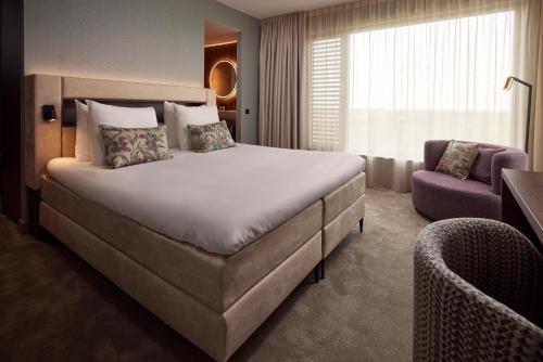 莱利斯塔德Van der Valk Hotel Lelystad的酒店客房带一张大床和一把椅子