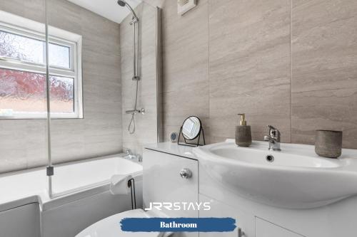 StockingfordNuneaton - Ideal 3 Bedroom, Wi-fi Parking, Sleeps 6 - JRR Stays的浴室配有盥洗盆、卫生间和浴缸。