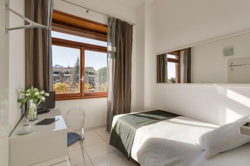 罗马迪瑞沃龙门塔拉酒店的一间卧室配有一张床、一张书桌和一个窗户。