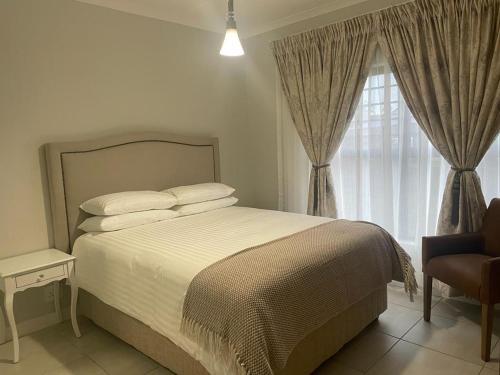比勒陀利亚Blyde Beach Front Apartment Ground floor的卧室配有床、椅子和窗户。