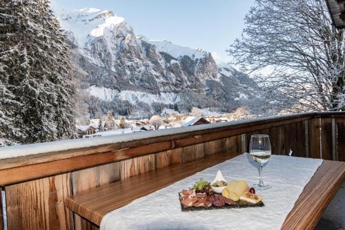 坎德施泰格Typically Swiss Hotel Ermitage的一张桌子,上面放着一盘食物和一杯葡萄酒