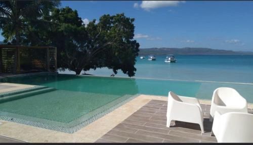 蓬塔露奇亚Hotel Sand Bay的一个带两把白色椅子和水的游泳池
