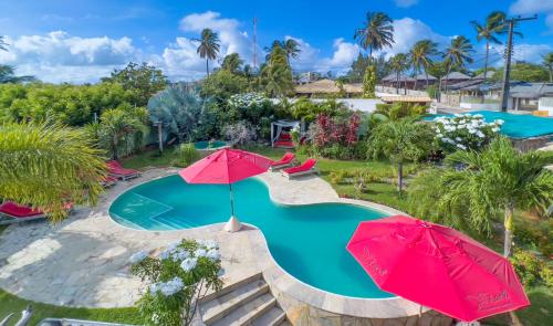 卡姆布库Xainã Pousada de Charme的享有带两把红伞的游泳池的顶部景致