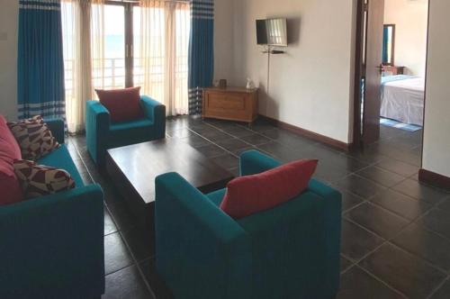 PamunugamaReef Bungalow Hotel的客厅配有2把蓝色椅子和桌子