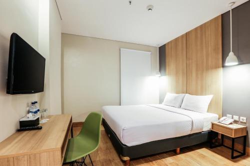 三宝垄三宝垄奇特拉瑞姆酒店的一间卧室配有一张床、一张书桌和一台电视。