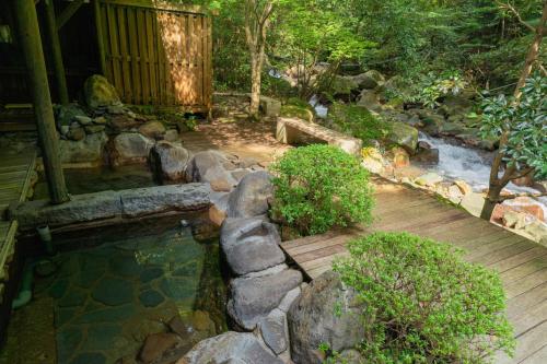 雾岛市Kirishima Momijidani Seiryuso的一个带池塘和木甲板的花园