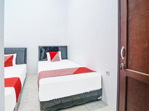 美娜多SPOT ON 91995 Cvictory Inn的一间卧室配有两张红色和白色床单