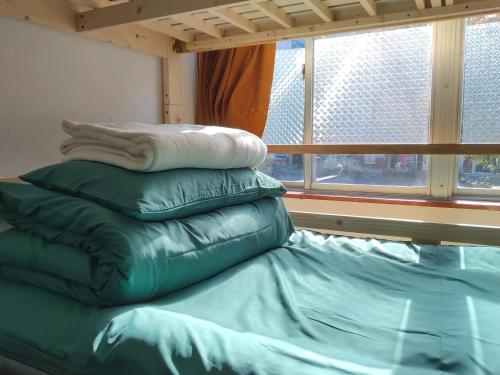 大阪Guest House mii的窗户间床上的枕头堆