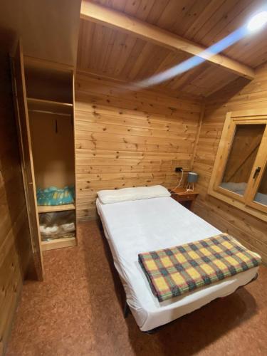 格劳斯Bungalow & Camping Fuente De Regrustan的木制客房内的一间卧室,配有一张床