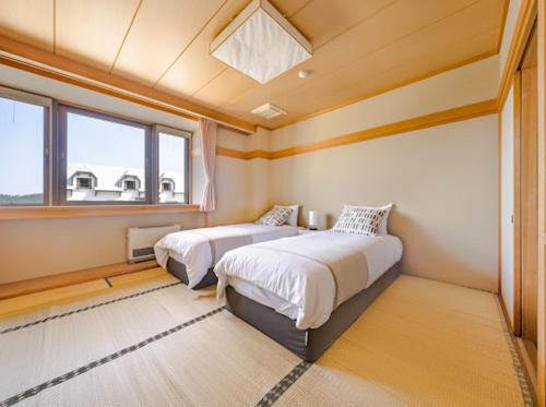 妙高Red Fox Lodge Myoko的一间卧室设有两张床和窗户。