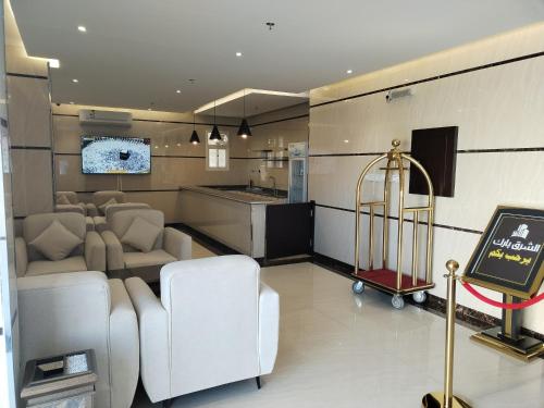 Al MikhlafAl Shark Park Serviced Apartment的一间带白色椅子的客厅和厨房