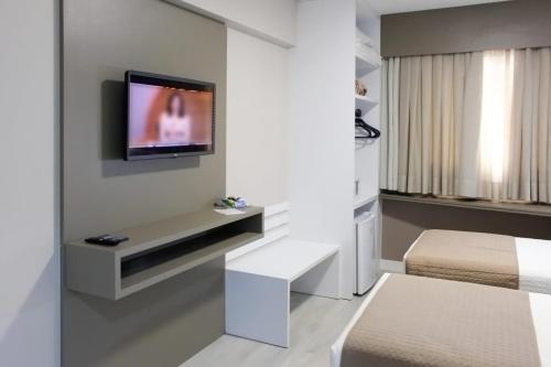 因达亚尔Tri Hotel Executive Indaial的一间设有两张床和一台墙上电视的房间