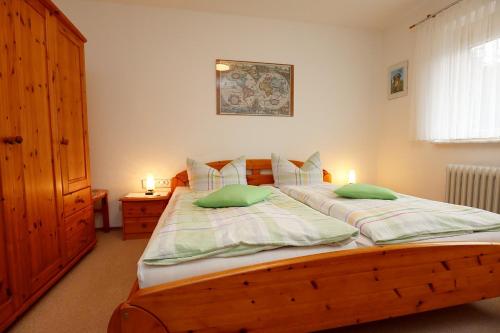 策尔阿姆哈尔梅尔斯巴赫格林达家庭旅馆的一间卧室配有一张带两个绿色枕头的木床
