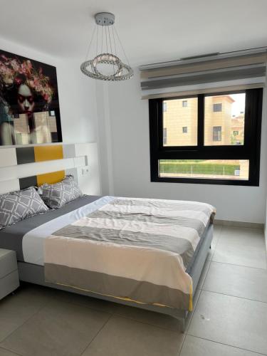 哈维亚VIVES con ALEGRIA的一间卧室设有一张床、一个窗户和一个吊灯。