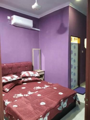 阿罗士打D'illahs Homestay的一间卧室设有紫色的墙壁和一张带红色床罩的床。