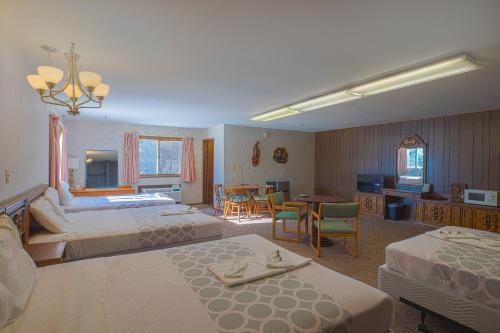TomahawkLove Hotels Tomahawk at Lake Mohawksin WI的酒店客房带两张床和一张桌子以及椅子。