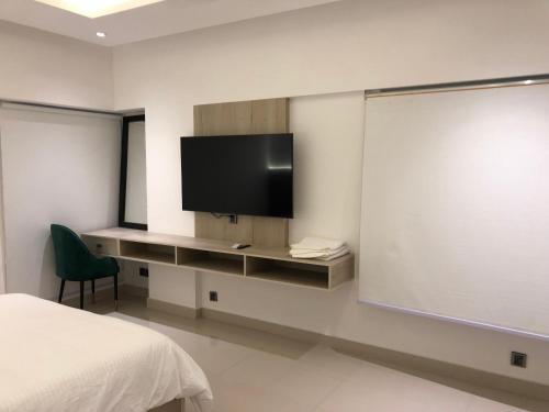 卡拉奇Hamsun Apart Hotel Clifton的一间卧室配有一张床,墙上配有电视