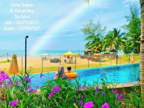 关丹TimurBay Seafront Residence at Casa Inara的坐在海滩旁游泳池里的男人