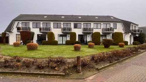 多鲁姆纽菲尔德Ferienwohnung am Kormoranweg的一座白色的大房子,有一座灌木丛的院子