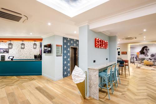 伯恩茅斯ibis Styles Bournemouth的一间设有酒吧、凳子和桌子的房间