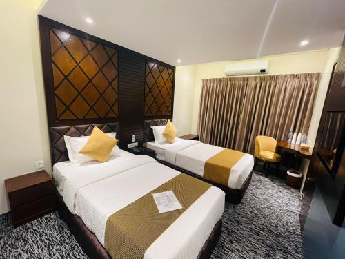 巴纳内拉斯Richmond Hotel Sylhet的酒店客房配有两张床和一张书桌
