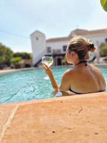 MelegisEl Violin Experiencia Adults only的坐在游泳池里拿着一杯葡萄酒的女人