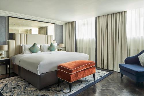 伦敦The Royal Horseguards Hotel, London的一间卧室配有一张大床和一张蓝色椅子