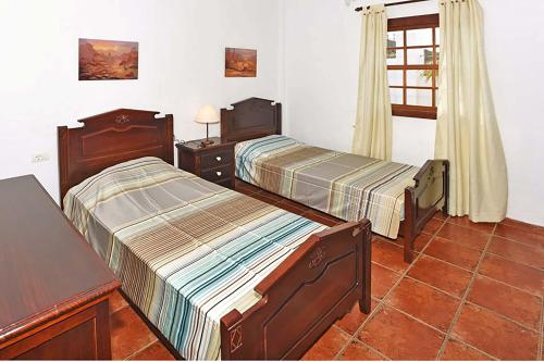 蒂哈拉费Villa Don Pedro的一间卧室设有两张床、一张桌子和一个窗口