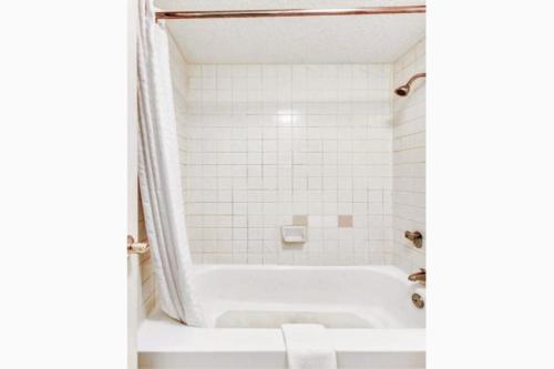 纳科多奇斯Quality Inn Nacogdoches Near University的带浴缸和白色瓷砖的浴室